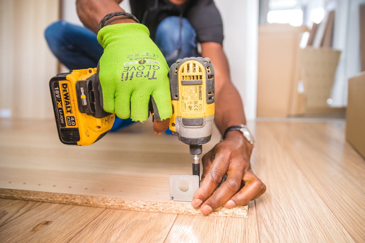 Services Man using a power drill for home improvement on a wooden floor with precision.